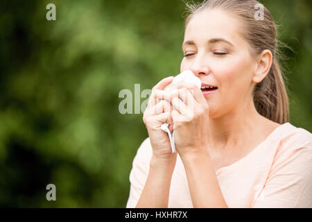 Frau mit einem kalten Niesen von Allergie oder Heuschnupfen Stockfoto