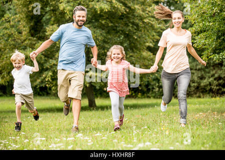 Fröhliche Familie mit zwei Kindern viel Spaß beim laufen im park Stockfoto