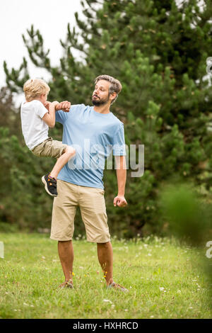 Vater und Sohn spielen Roughouse im Sommer als Familie Stockfoto