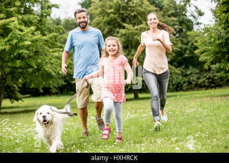 Mädchen und Eltern mit Golden Retriever als Familie im park Stockfoto