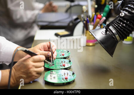 Electronics Manufacturing Services, manuelle Montage der Platine Löten, Nahaufnahme der Hand Frauen halten Werkzeug. Stockfoto