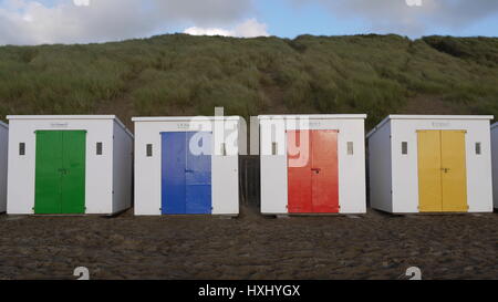 4 Strandhütten auf Woolacombe Strand jeweils mit einer anderen Farbe Tür. Stockfoto