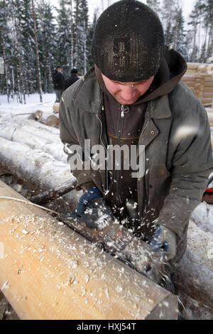 Gebiet Leningrad, Russland - 2. Februar 2010: Arbeitnehmer richtet das Protokoll mit Hobel. Stockfoto