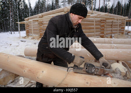 Oblast Leningrad, Russland - 2. Februar 2010: Bau eines Log cabin, eines Protokolls durch eine elektrische Hobel hobeln. Stockfoto