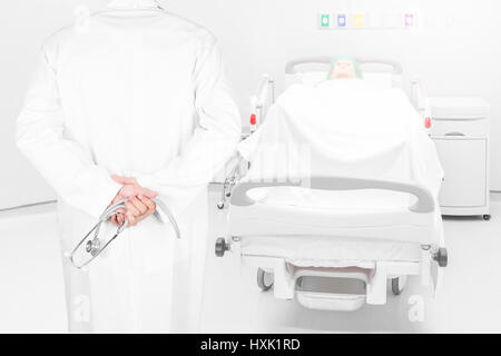Close-up Rückansicht Bild von Ärzten mit Stethoskop darstellen Arme verschränkt hinter Blick zurück auf Pateint Bett im Krankenzimmer Stockfoto
