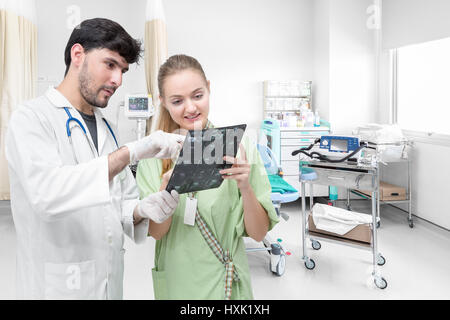 Arzt untersucht einen Röntgenfilm und diskutieren mit einem Patienten im Krankenzimmer Stockfoto