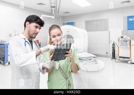 Arzt in CT Untersuchungsraum Untersuchung eine Röntgenaufnahme und diskutieren mit einem Patienten Stockfoto