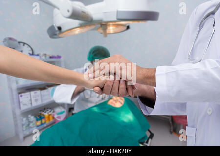Hand der Ärzte zu beruhigend Verwandten des Patienten, den Behandlung gut läuft Stockfoto