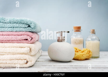 Handtücher mit Flaschen Shampoo und Meer Salz auf hellem Hintergrund Stockfoto