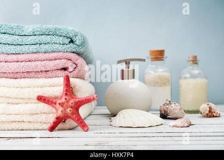 Handtücher mit Flaschen Shampoo und Meer Salz auf hellem Hintergrund Stockfoto