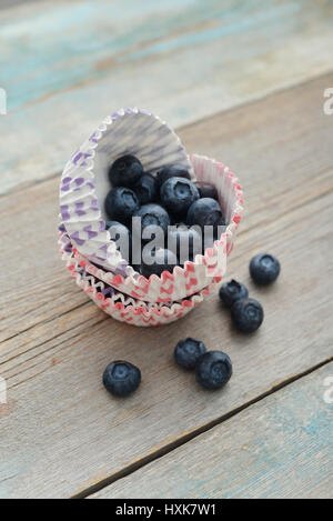 Cupcake-Fällen mit Heidelbeeren auf hölzernen Hintergrund Stockfoto