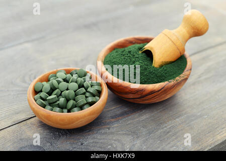 Boden-Spirulina und Spirulina in Pillen über schwarzen Holz Hintergrund Stockfoto