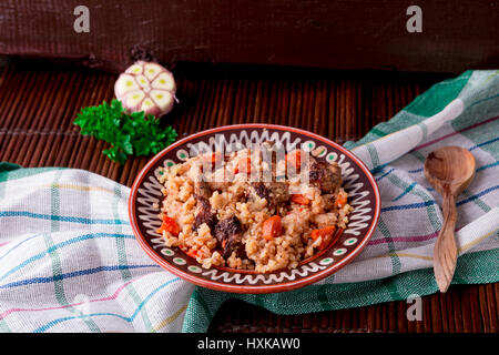 Pilaw auf die braune Platte auf einem Holztisch, Hintergrund. Rustikaler Stil Stockfoto