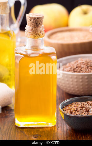 Nonrefined Leinsamen-Öl in eine Flasche und braunen Leinsamen in Schüssel auf Holztisch. Vertikale erschossen Stockfoto