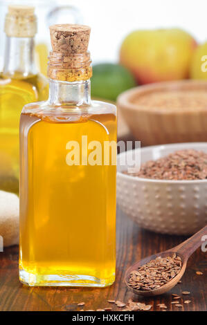 Brauner Leinsamen auf Löffel und nonrefined Leinöl in Glasflasche auf Holztisch. Vertikale erschossen Stockfoto