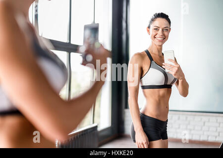 Junge sportliche Frau, die die Spiegel Selfie im Fitness-Studio Stockfoto