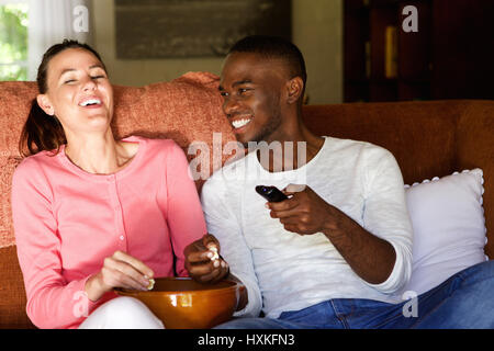 Porträt des jungen Brautpaares auf Sofa Film und Essen Popcorn zu Hause sitzen Stockfoto