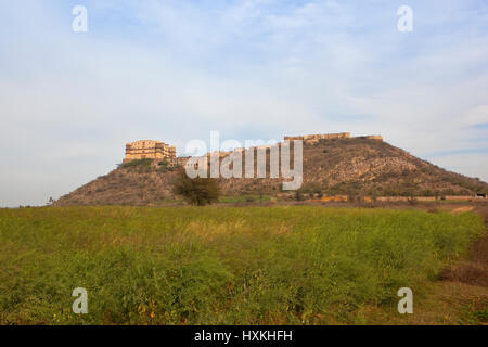 TIJARA Fort Palasthotel auf einem Hügel in der landwirtschaftlichen Umgebung von Rajasthan mit Reifung Senf Anbau unter bewölktem Himmel blau Stockfoto