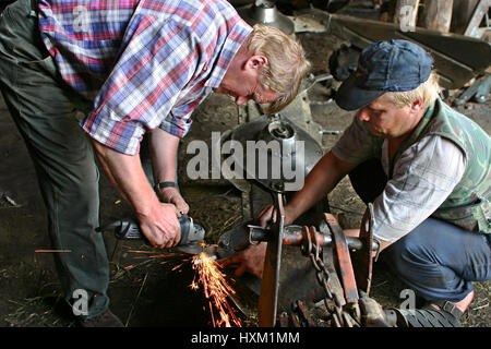 Lemozero, Olonez, Karelien, Russland - 26. Juli 2006: Zwei Bauern Bauernhof Traktor Mähen-Maschine repariert in einer Reparaturwerkstatt schärfen Messer mit einem grind Stockfoto