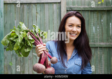 Porträt einer lächelnden vegetarisch-Frau mit Haufen von rote Beete Stockfoto