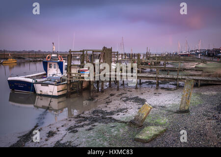 Die Reste eines Regenbogens verblassen über die Fischerboote vertäut an der Pontons auf Blackshore in Southwold, Suffolk, im Morgengrauen Mitte März. Stockfoto