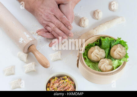 Hände, die hausgemachte Dim Sum asiatische Teigtaschen Brötchen vorbereiten Stockfoto