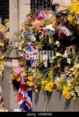 Westminster, London, UK. 27. März 2017. Blumen und Fahnen links als Tribut auf dem Geländer des Parlaments an die Gefallenen der Terror-Attac erinnern Stockfoto