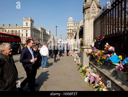 Westminster, London, UK. 27. März 2017. Menschen betrachten die floral Tribute links auf dem Geländer des Parlaments zu den getöteten im ter erinnern Stockfoto
