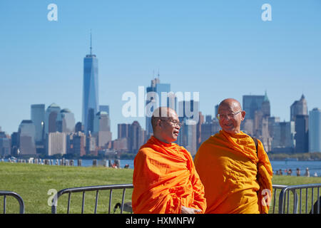 Zwei buddhistische Mönche mit Orange Kleid vor der Skyline von New York City an einem sonnigen Tag, blauer Himmel Stockfoto