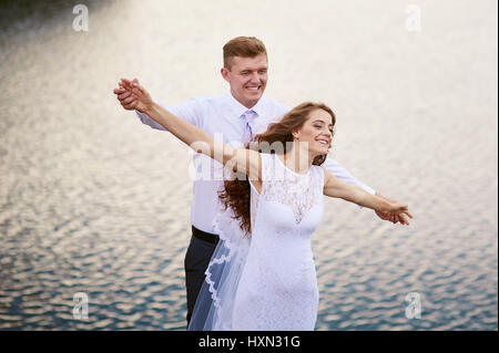 Glückliche Braut und Bräutigam auf eine Hochzeit gehen in der Nähe der See-Umarmung Stockfoto