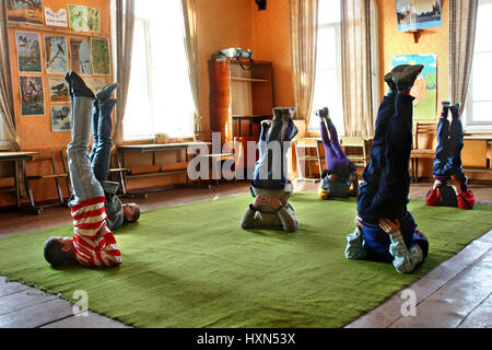 Twer, Russland - 2. Mai 2006: Sportunterricht stellen ländlichen Schulkinder tun Übung Schulterstand, Kerze-pose Stockfoto