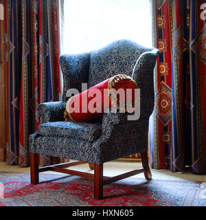 Gemusterten Sessel mit roten Kissen. Stockfoto