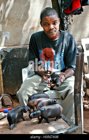 Namanga, Tansania - 9. Februar 2008: Junge schwarze Afrikaner, Holzschnitzer, Kunstwerkstatt arbeiten.  Dunkel-enthäutete master Holzschnitzerei, Polieren aus Holz Stockfoto