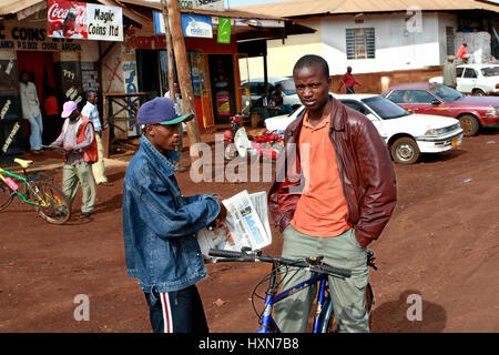 Makuyuni, Arusha, Tansania - 13. Februar 2008: Junge schwarze afrikanische Männer trafen sich auf der Dorfstraße, ein Betrieb einer Zeitung Mwananchi, mit Text in Swa Stockfoto