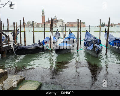 Venezianische Gondeln festgemacht im Regen von Markusplatz entfernt mit Käse di San Giorgio Maggiore im Hintergrund, Venedig, Italien Stockfoto