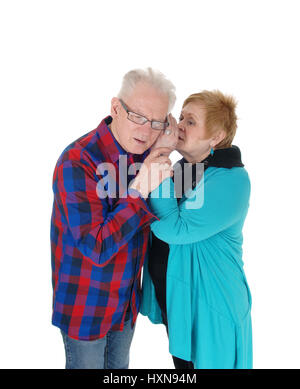 Eine ältere älteres paar stehen isoliert für weißen Hintergrund und die Frau ist einige Gerüchte ins Ohr flüstern. Stockfoto