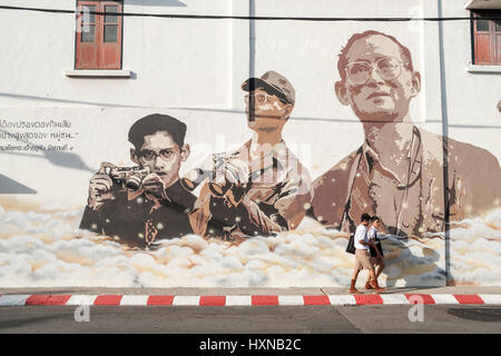 Thailändische Schüler in Phuket Altstadt pass eine Wandbild im Gedenken an König Bhumibol Adulyadej.  Als Thailand trauern den König Denkmäler zur Erinnerung an die Stockfoto