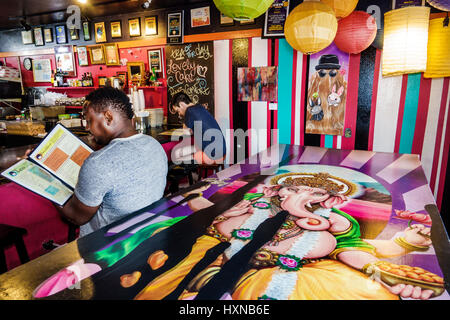 Orlando Florida, Pom Pom's Teehaus & Sandwicheria, Kaffeehaus, Café, Theke, Dekor, Schwarze Männer männlich, sitzen, Menü lesen, bemalter Tisch, Ganesha, Ganapat Stockfoto