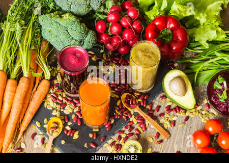 Gesunde vegane Ernährung. Frisches Gemüse auf hölzernen Hintergrund. Detox-Diät. Verschiedene bunte frische Säfte Stockfoto