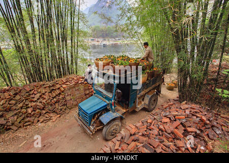 YANGSHUO, GUANGXI, CHINA - 29 März: Beförderung von orange Ernte im Südwestchinas, 29. März 2010. Old-Time blaue LKW mit einem Weidenkorb mit o Stockfoto