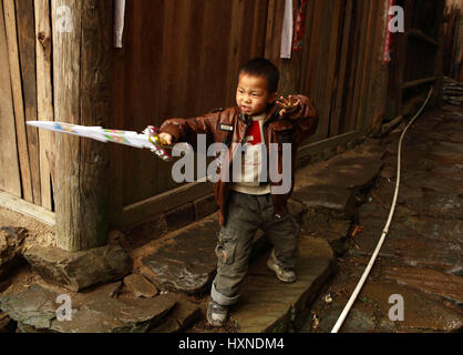 Provinz GUANGXI, CHINA - APRIL 4: Chinesische junge 6 Jahre alt, spielen mit Kunststoff Schwert in der Nähe von Holzhaus im Dorf Xiaozhai, 4. April 2010. Dorf ich Stockfoto