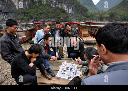 Yang Di Dorf, Yangshuo, Guangxi, China - 29. März 2010: chinesische Schiffer Männer Spielkarten in der Nähe von Pier am Hintergrund der Karst Hügeln, Li-Fluss, Guang Stockfoto