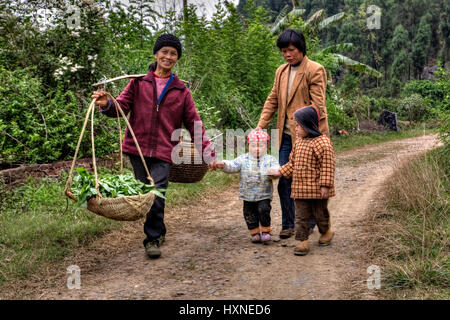 Yang Di Dorf, Yangshuo, Guangxi, China - 29. März 2010: Land Straße in Ackerland ist zu Fuß auf asiatischen Familie, Frauen und Kinder, Landwirt trägt auf Stockfoto