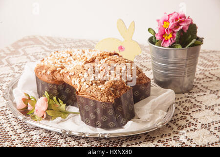 Ostern Taube auf einem Brett mit Spitzen Tischdecke und ein Glas mit Primeln. Stockfoto