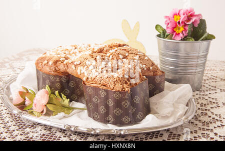 Ostern Taube auf einem Brett mit Spitzen Tischdecke und ein Glas mit Primeln. Stockfoto