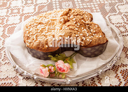 Ostern Taube auf einem Brett mit Spitzen Tischdecke und ein Glas mit Primeln. Stockfoto