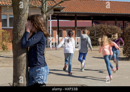 Kinder in der Grundschule spielen verstecken und suchen in Pause Stockfoto