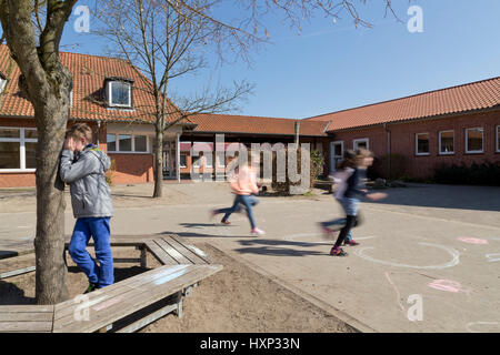 Kinder in der Grundschule spielen verstecken und suchen in Pause Stockfoto