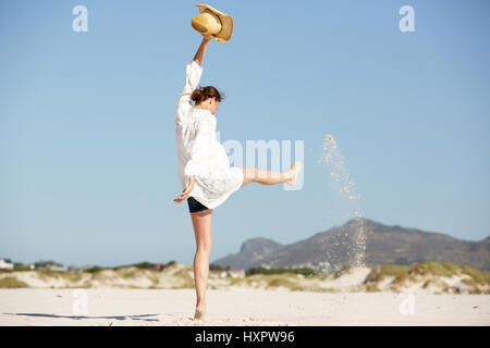 In voller Länge Portrait von erregte junge Frau treten Sand am Strand Stockfoto