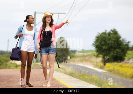 Porträt von zwei jungen Freundinnen zu Fuß entlang einer Eisenbahnstation und Blick auf einen Blick Stockfoto